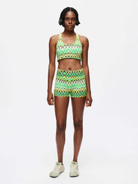Model wearing Doing Things Bra with matching shorts in vibrant green zigzag pattern, perfect for activewear.
