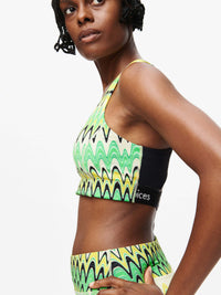 Woman wearing Doing Things Bra in vibrant green wave pattern, showcasing mesh backing and Outdoor Voices logo.