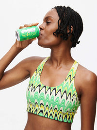Doing Things Bra worn by a model sipping Joosy Energy drink, showcasing its vibrant design and style.