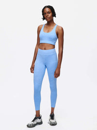 A model wearing the Doing Things Bra in blue, showcasing its high-performance design and mesh backing.