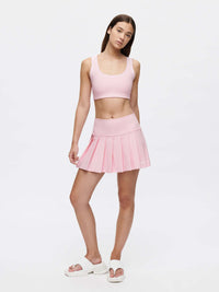 Model wearing a pink Doing Things 3" Skort with built-in shorts, showcasing pleated design and silicone gripper band.