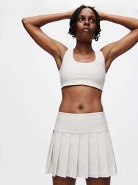 Model showcasing the Doing Things 3" Skort in light color, featuring pleats and built-in shorts for active wear.