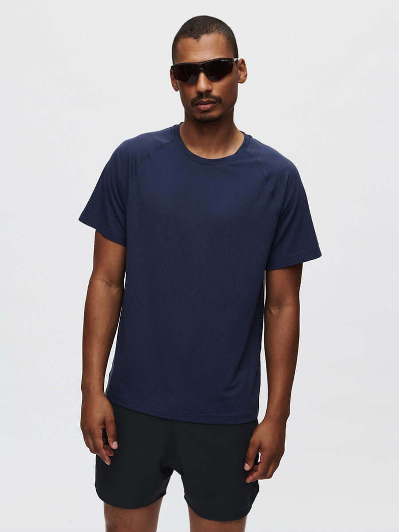Model wearing High Stride 5" Short with Pockets and a navy tee, ready for training and recreation.