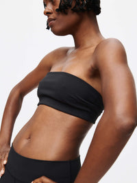 Model wearing the Love Bra, a low-impact bandeau top in sleek black, designed for stylish movement and comfort.