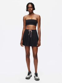 Model wearing the Stardust Skirt featuring pleats, side zipper, and drawstring tie in lightweight fabric.