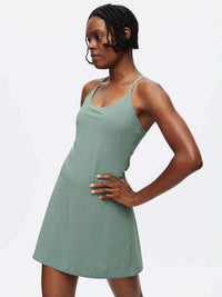 Model in a confident pose wearing The Exercise Dress in Sage Green with adjustable straps and a built-in shorts liner.