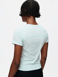 Back view of a model wearing the ThinkFast Jersey Baby Tee in soft mint color.