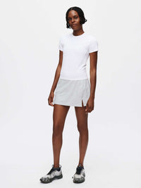 Model wearing the ThinkFast Jersey Baby Tee with a sporty gray skirt, perfect for active recreation.