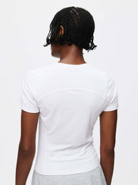 Back view of a model wearing the ThinkFast Jersey Baby Tee in white, showcasing its breathable and stylish design.