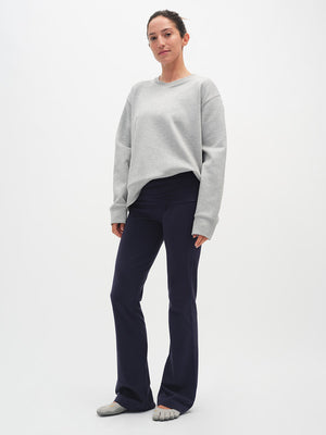Woman wearing a gray sweater and dark pants on a white background