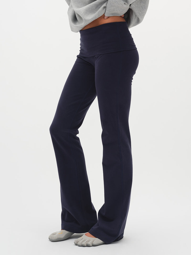 Woman wearing a gray sweater and dark pants on a white background