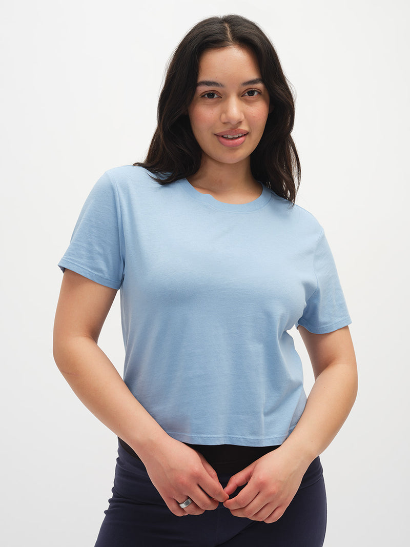 Woman wearing a light blue t-shirt against a plain background