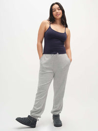 Woman wearing a navy tank top and gray sweatpants on a white background