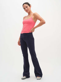Woman wearing a pink tank top and navy pants on a white background