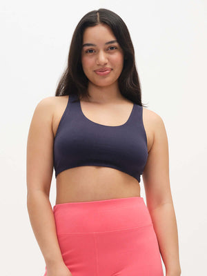 Woman wearing a dark blue sports bra and pink leggings on a white background