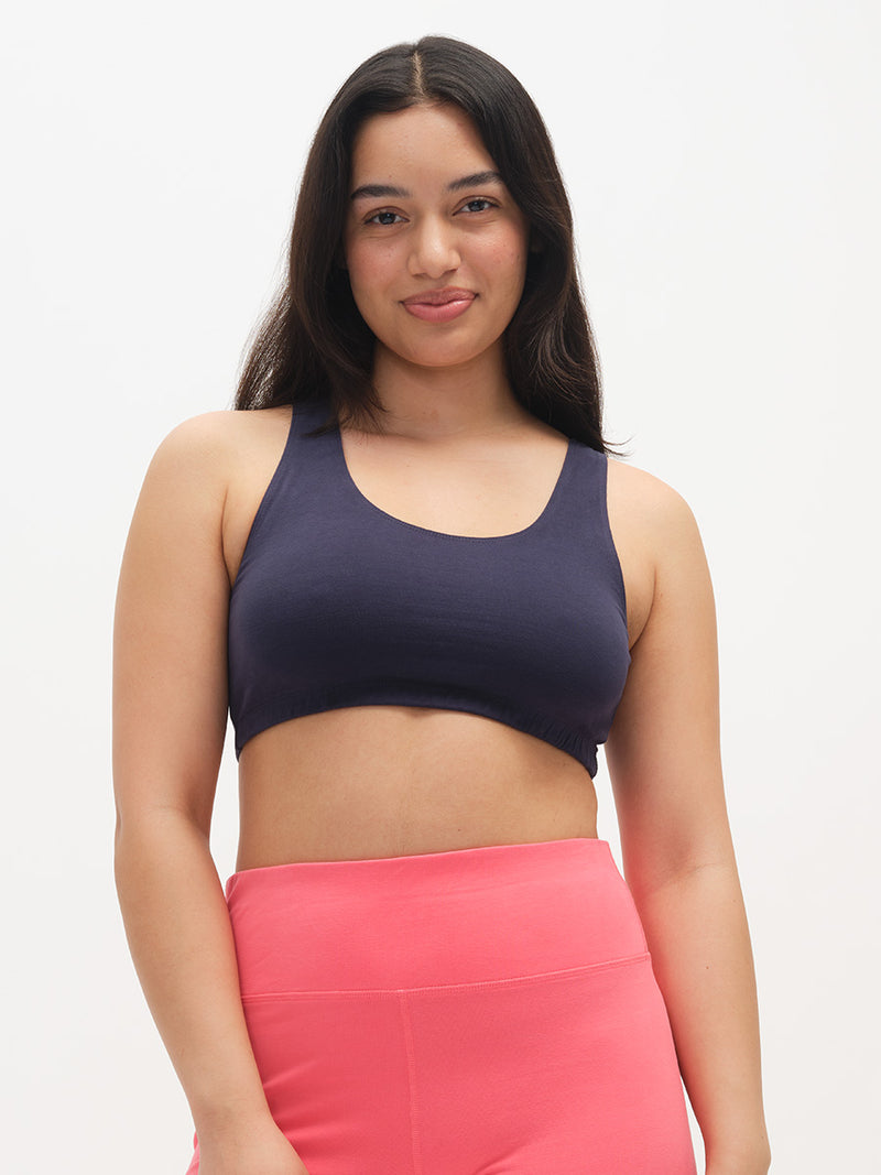 Woman wearing a dark blue sports bra and pink leggings on a white background