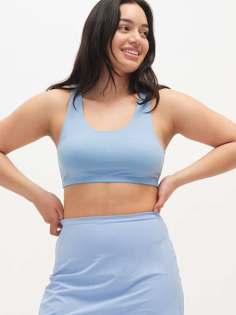 Woman wearing a light blue sports bra and skirt on a white background