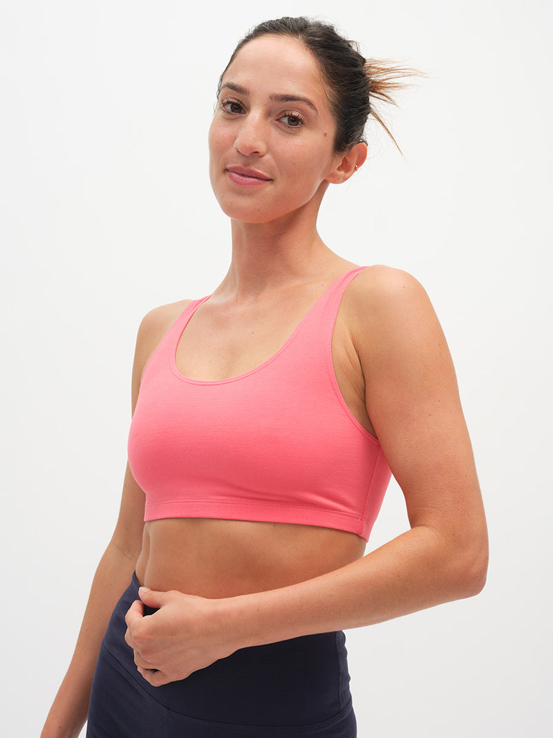 Woman wearing a pink sports bra and dark pants on a white background