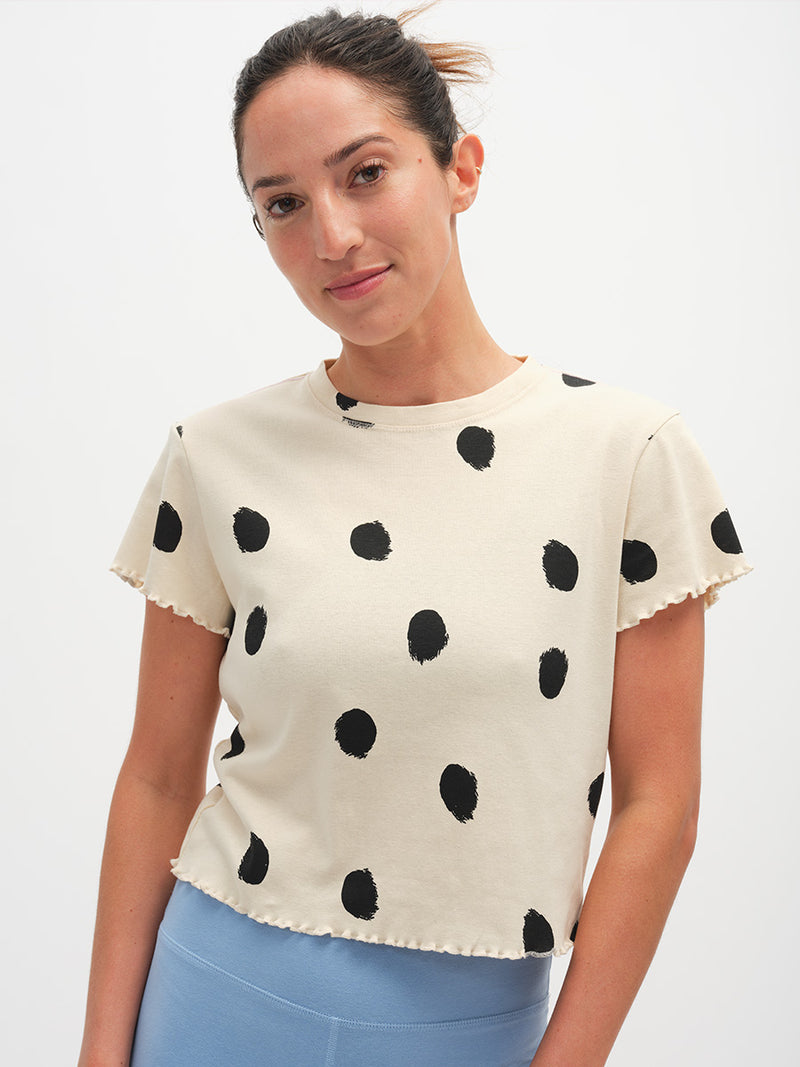 Woman wearing a cream blouse with black polka dots on a white background