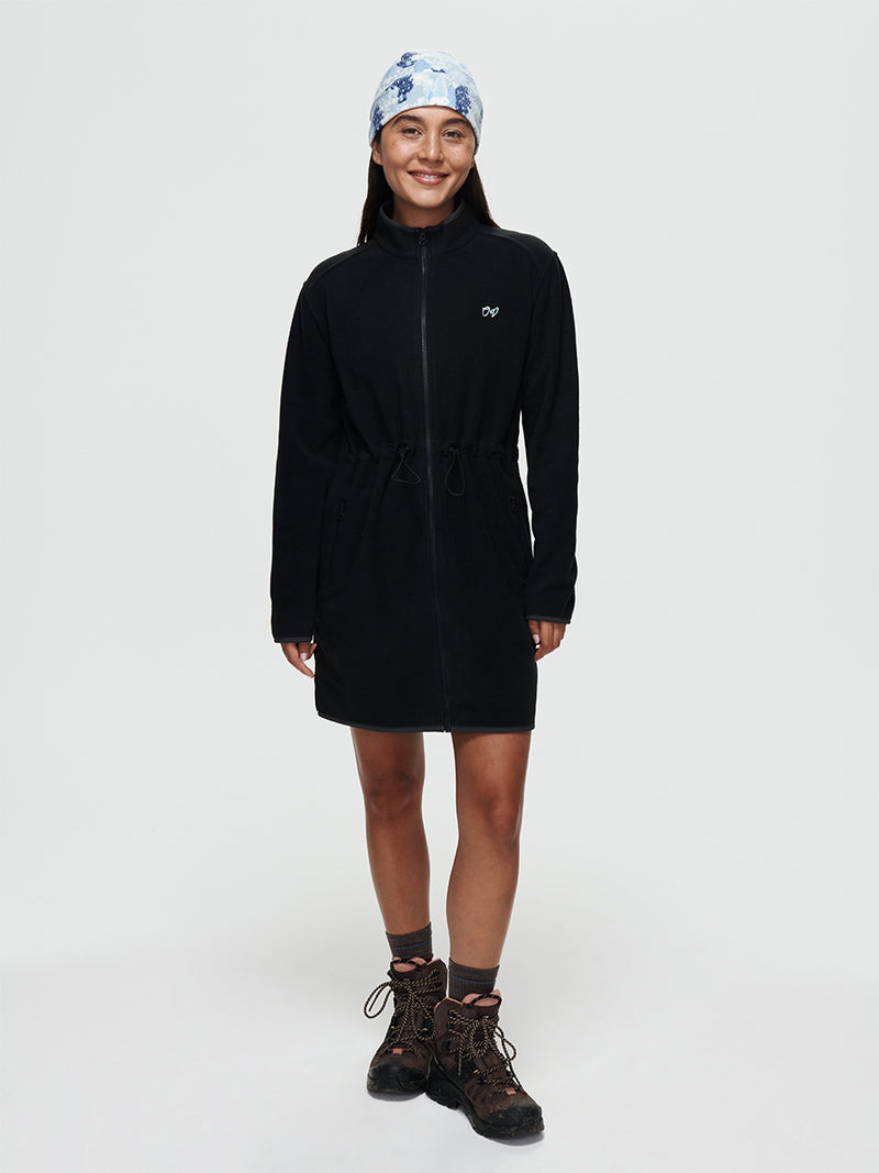Model wearing the Boulder Dress, a long-sleeve full-zip dress in black with adjustable waist toggles.