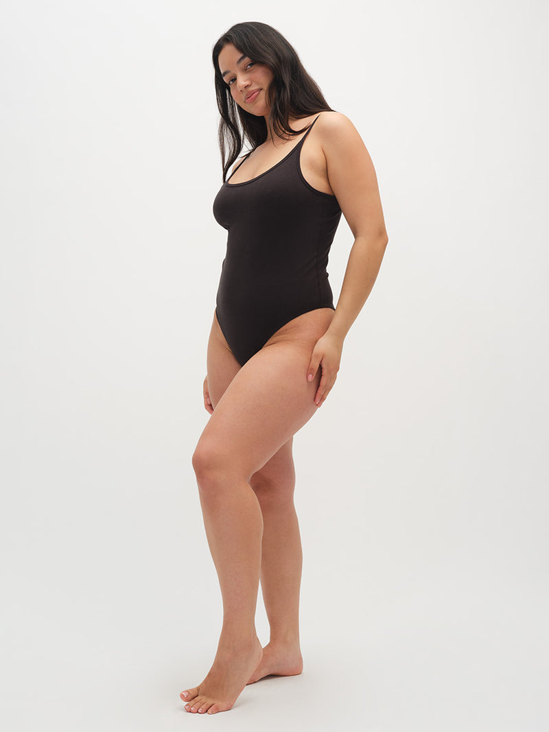 Woman wearing a black bodysuit on a white background
