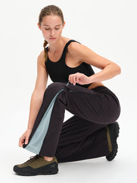 RecTrek Zip Pant in Black Multi – kneeling view unzipping the side zip at the hem