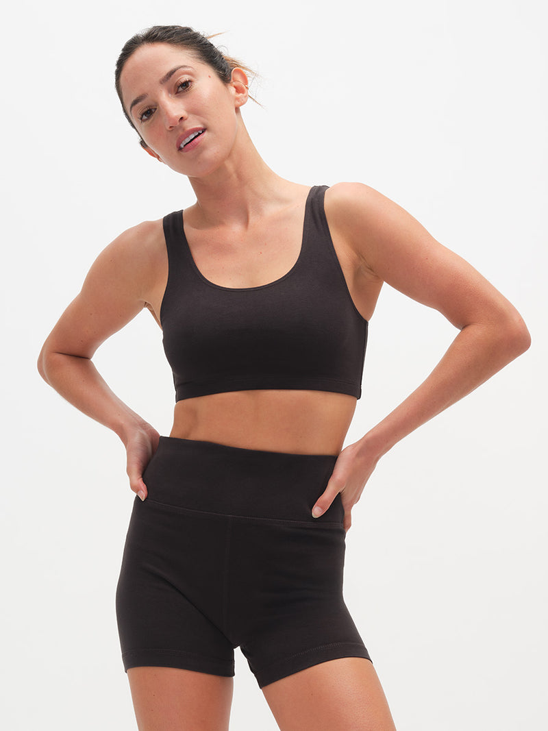 Woman wearing a black sports bra and shorts on a white background