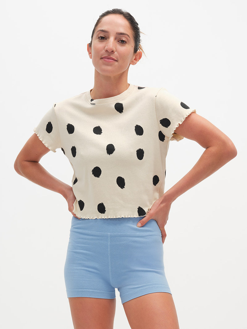 Woman wearing a polka dot top and light blue shorts on a white background