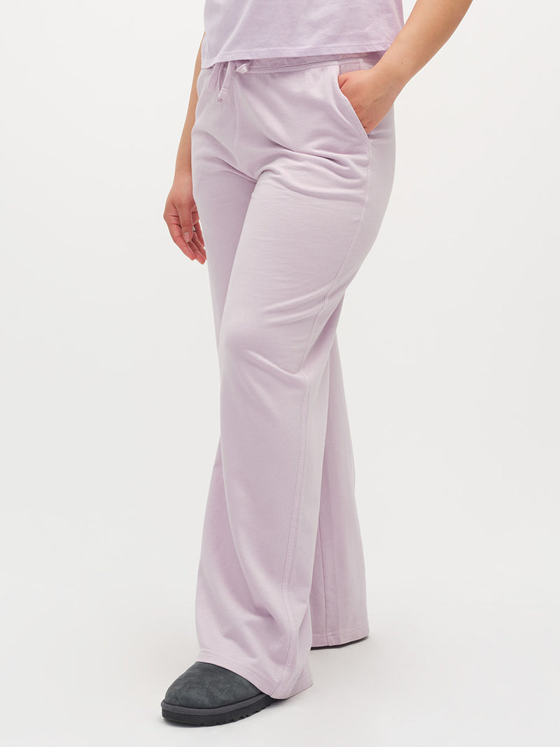 Person wearing light purple lounge pants and a matching top on a white background