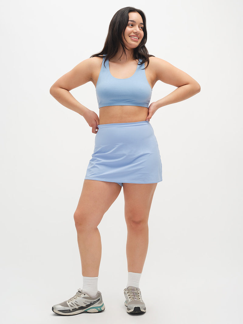Woman wearing a light blue athletic outfit on a white background