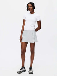 Model wearing a Warmup 2.5" Skort with a white t-shirt and athletic shoes, showcasing the skort's performance fabric.