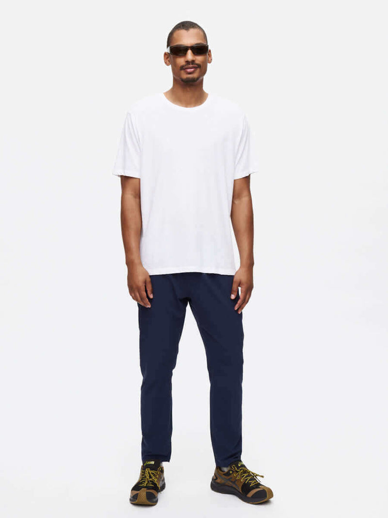 Man wearing Zephyr Pant in navy with a white t-shirt and sunglasses, showcasing lightweight performance for everyday activities.