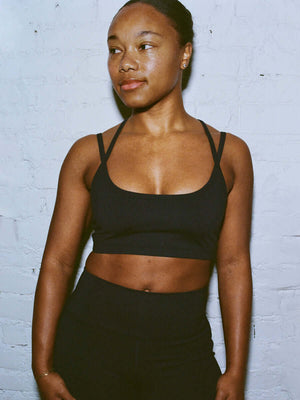 Model posing in Apple Bra in Black with plunging neck and intersecting straps, styled for everyday wear.