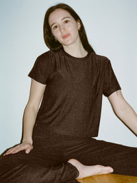 Model sitting in a relaxed pose wearing CloudKnit Boxy Shortsleeve in Charcoal, featuring a comfort-first, cropped design.