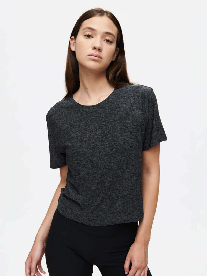 Model posing in CloudKnit Boxy Shortsleeve, charcoal gray, featuring a relaxed cropped fit.