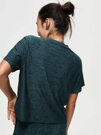 Woman wearing CloudKnit Boxy Shortsleeve shirt from the back, with the lightweight fabric and cropped design.