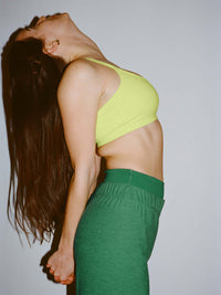 Model stretching in Apple Bra with plunging neck in Bright Yellow, soft Bubble Wrap material.