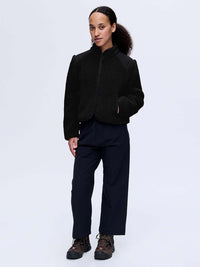 Model wearing Candy Fleece Jacket in Black with contrast nylon panels, styled for outdoor activities.