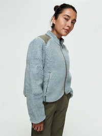 Model wearing Candy Fleece Jacket in Light Blue, featuring contrast nylon panels and zippered front pockets.