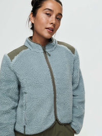 Model wearing Candy Fleece Jacket in Soft Blue, featuring contrast technical nylon panels and zippered pockets.