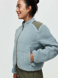 Model wearing Candy Fleece Jacket in light blue, featuring contrast nylon panels and a mock neck.