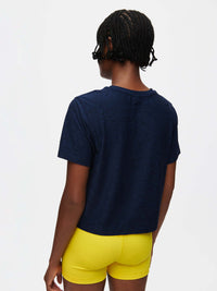 Back view of CloudKnit Boxy Shortsleeve in Navy, cropped length paired with bright yellow shorts.