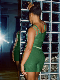 Model in slim fit CloudKnit Cami in Green, featuring adjustable straps, posing near a mirror.