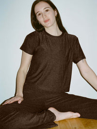 Model seated wearing CloudKnit Wide Leg Pant in Charcoal with a relaxed fit and matching short sleeve top.