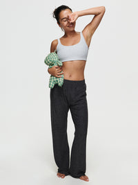 Model smiling while holding a stuffed toy, wearing CloudKnit Wide Leg Pant in Black, relaxed fit for lounging.