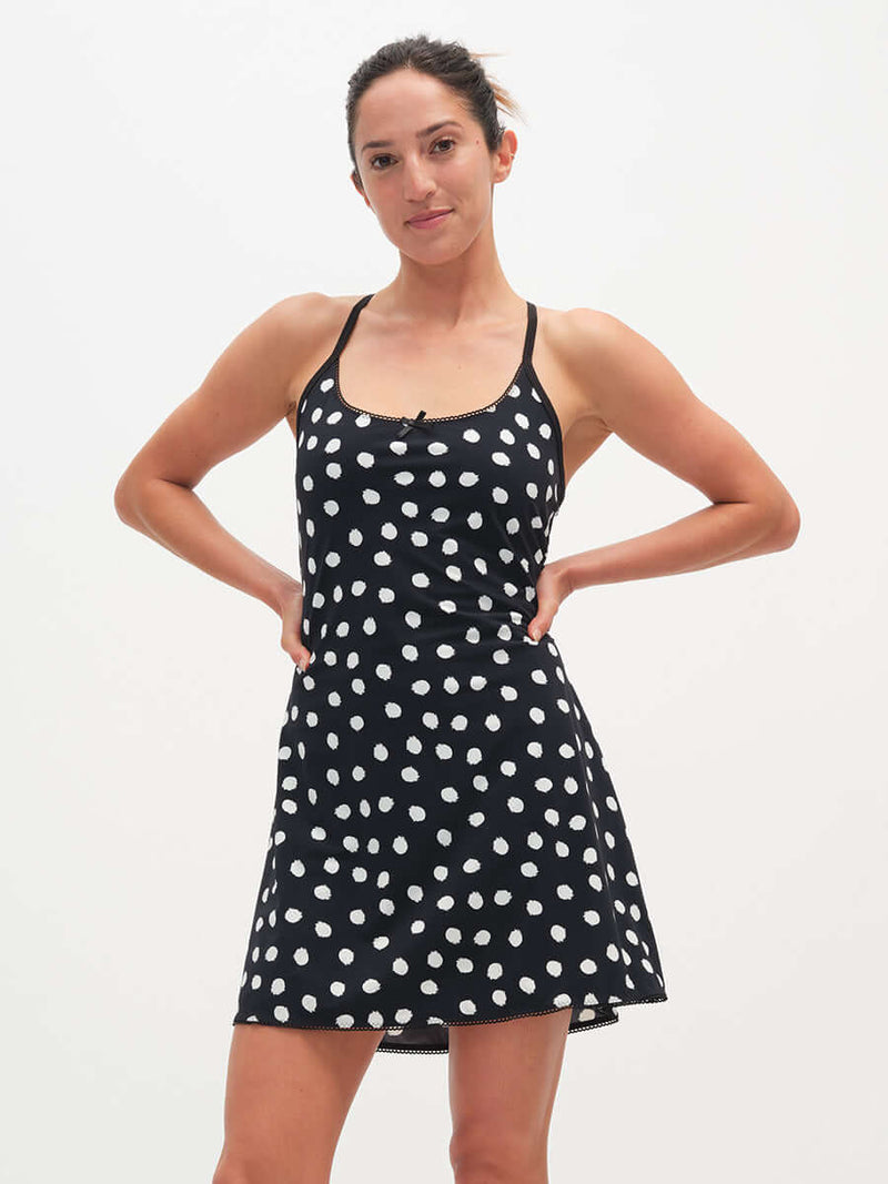 Model wearing Club Dress in Black with white polka dots, featuring adjustable straps and a cute bow detail.