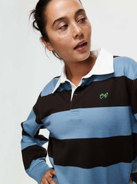 Woman wearing a Club Polo in blue and black stripes, with ribbed cuffs and hand-embroidered OV signature.
