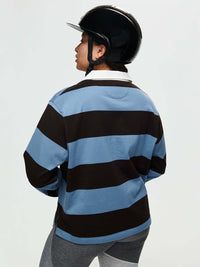 Model wearing a Club Polo with blue and brown stripes, with the woven collar and ribbed cuffs, for fall layering.