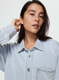 Close-up of model wearing Desert Shirt in light blue, with brushed silver buttons and oversized fit.