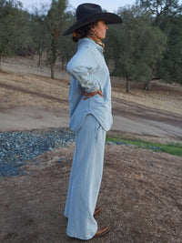 Model standing in profile wearing Desert Shirt in light blue, featuring an oversized fit and curved hem.